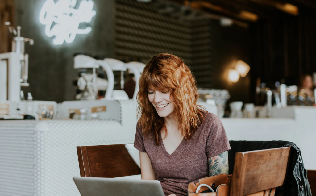 Women happily sitting in coffee shop looking at a computer