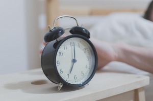 Picture of a hand reaching out to an alarm clock